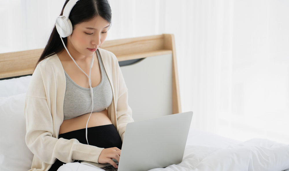 Asian Pregnant Women Wearing Headphone Using Laptop To Tele Health
